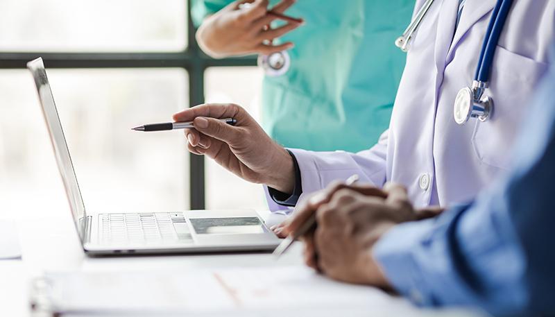 Team, medical analysts and doctors consulting with paperwork of graphs, data and charts in hospital conference room. Healthcare staff discussing statistics, results of research and innovation.