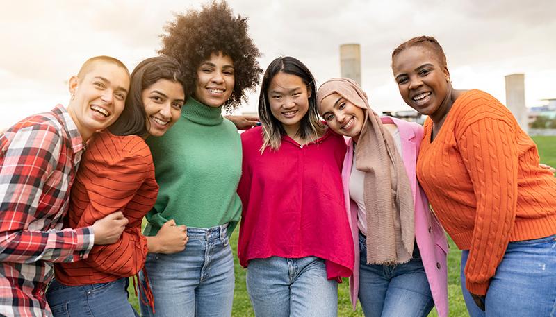 group of happy multiracial young friends hugging in the park - concept of women students from all over the world gathered