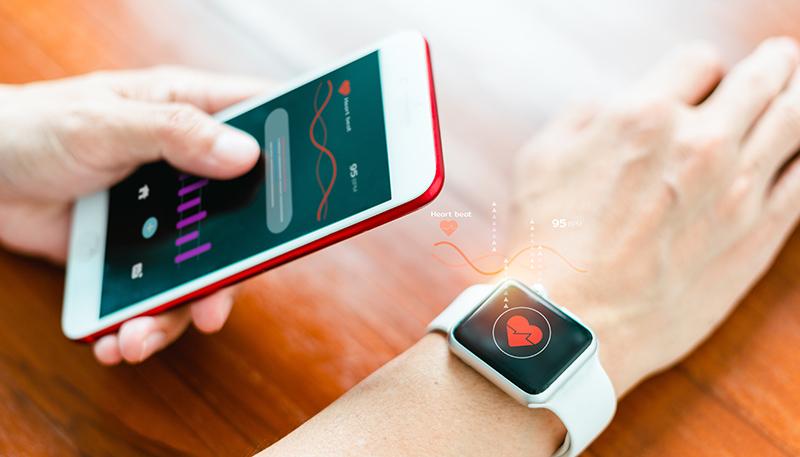 Close-up of a smart watch health tracker with the heart rate shown on the watch and smartphone screens. Modern stylish and innovation wearable device