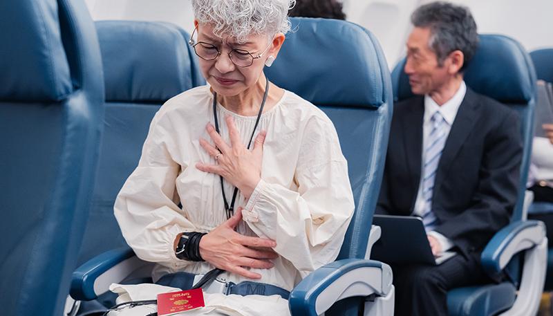 飛行機の機内で体調不良に苦しむ高齢の女性