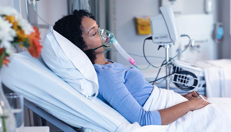 Sleeping african american female patient in hospital bed with oxygen ventilator