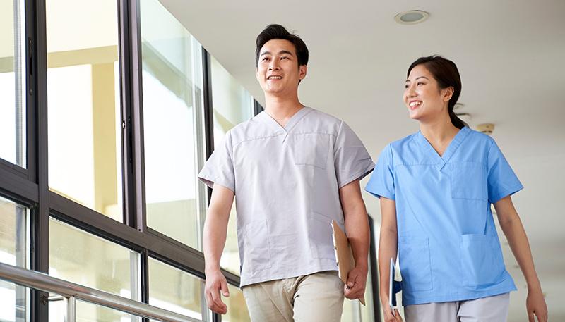 two healthcare professional coworkers walking talking in hospital hallway