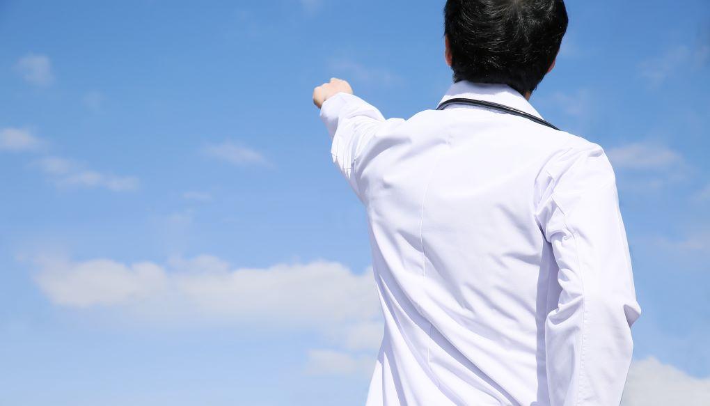 転職で後悔しないために未来を見据えて広い空に指をさしている医師の姿