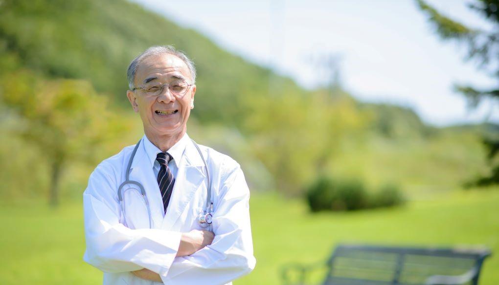 年配の医師が笑顔で腕を組んでいる写真