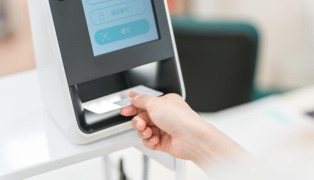 薬局・病院でマイナンバーカードをカードリーダーの機械で読み込む女性