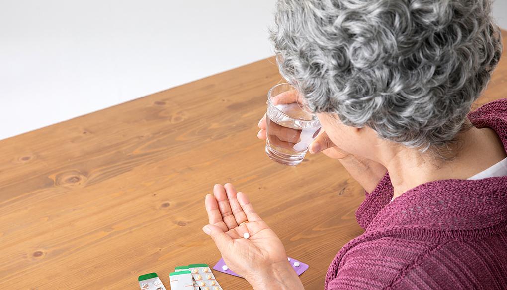 薬を飲む高齢女性