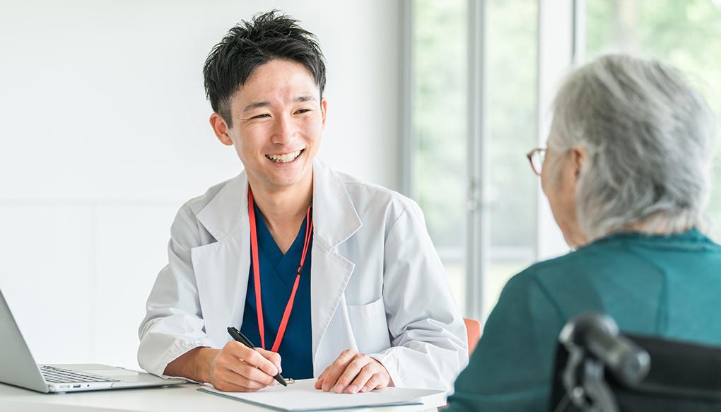 病院・介護施設で高齢者女性を診察・問診する男性医師（かかりつけ医）
