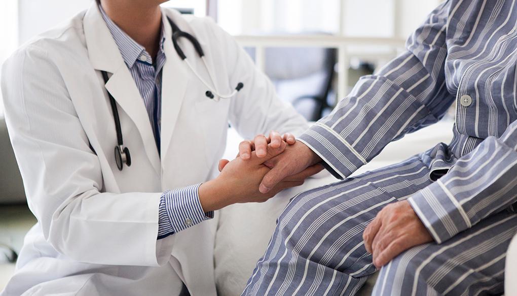 地域包括医療病棟（地メディ病棟）のベッドで医師の診断を受ける高齢者の男性