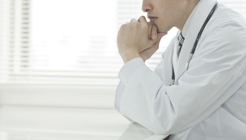 顎に手を置く医師の写真