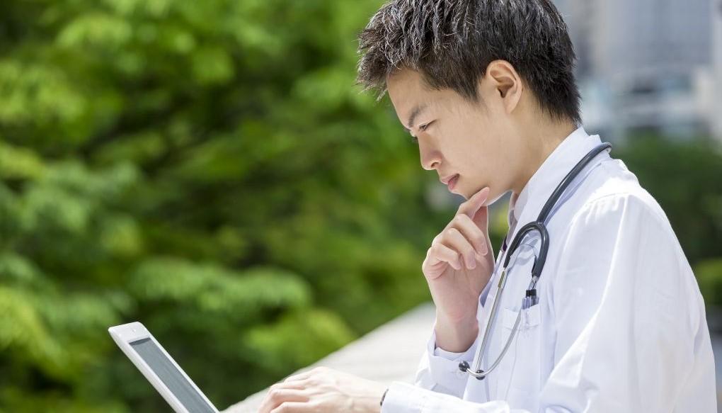PCを見ながら悩んでいる医師