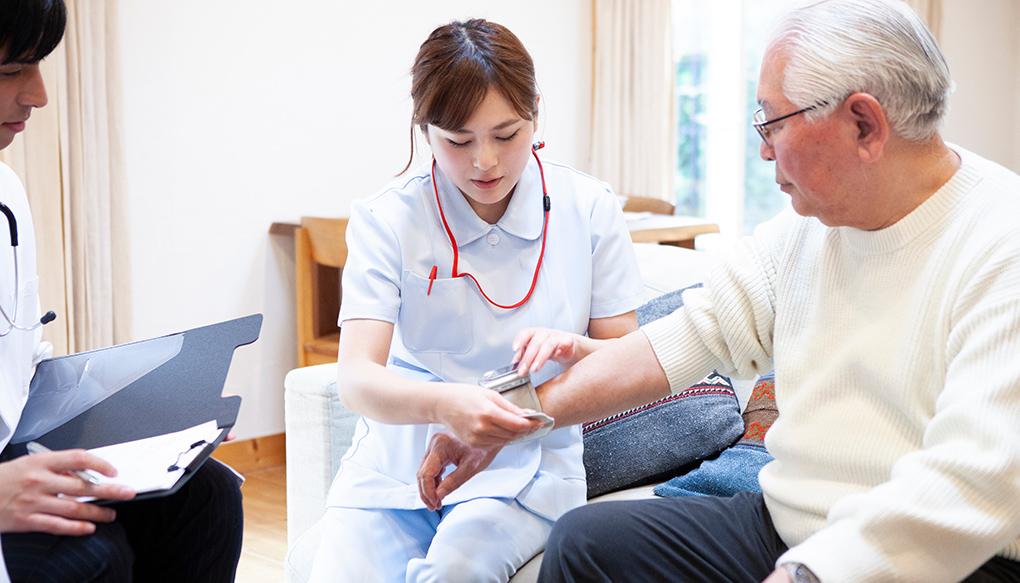 在宅医療で患者の血圧を図る看護師と医師