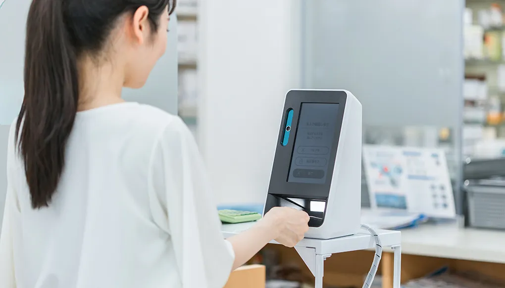 薬局・病院でマイナンバーカードをカードリーダーの機械で読み込む女性